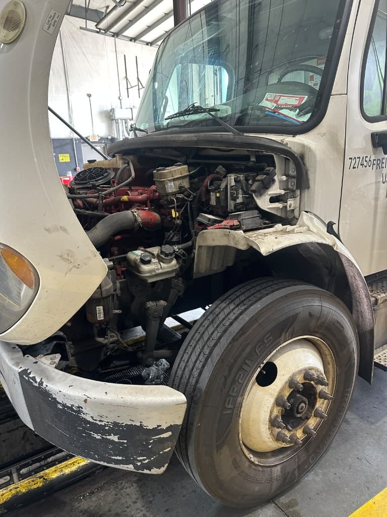 Heavy-duty Freightliner with hood open for service in the shop bay